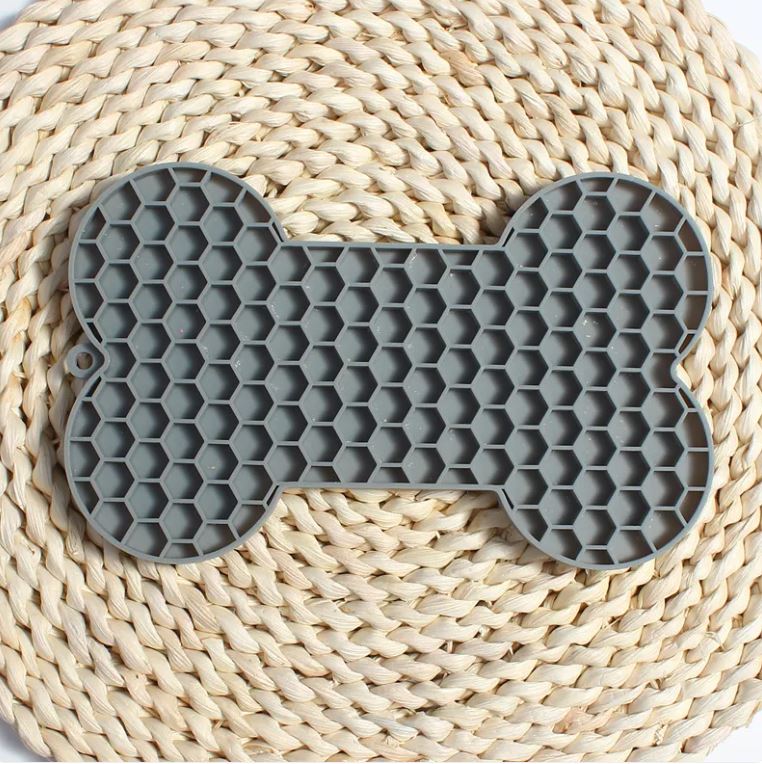 Gray bone-shaped silicone dog slow feeder lick mat with raised honeycomb texture, size 18 x 11 x 1 cm and weight 55 g shown on image